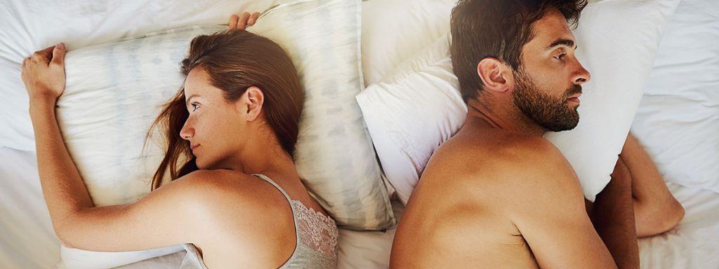 Egy pár vitázik az ágyban, a nemi szervi szemölcs okozta párkapcsolati feszültség miatt.